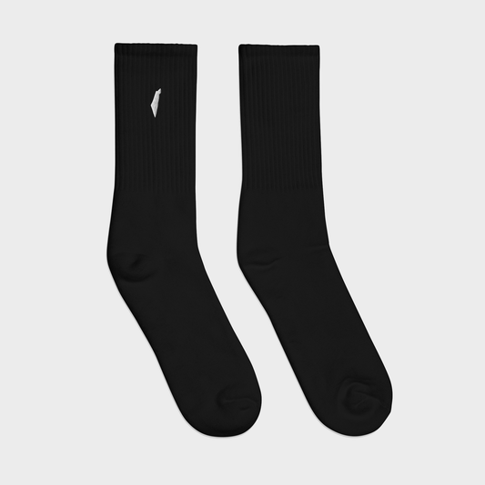 Pair of black socks with a small white logo on a light gray background